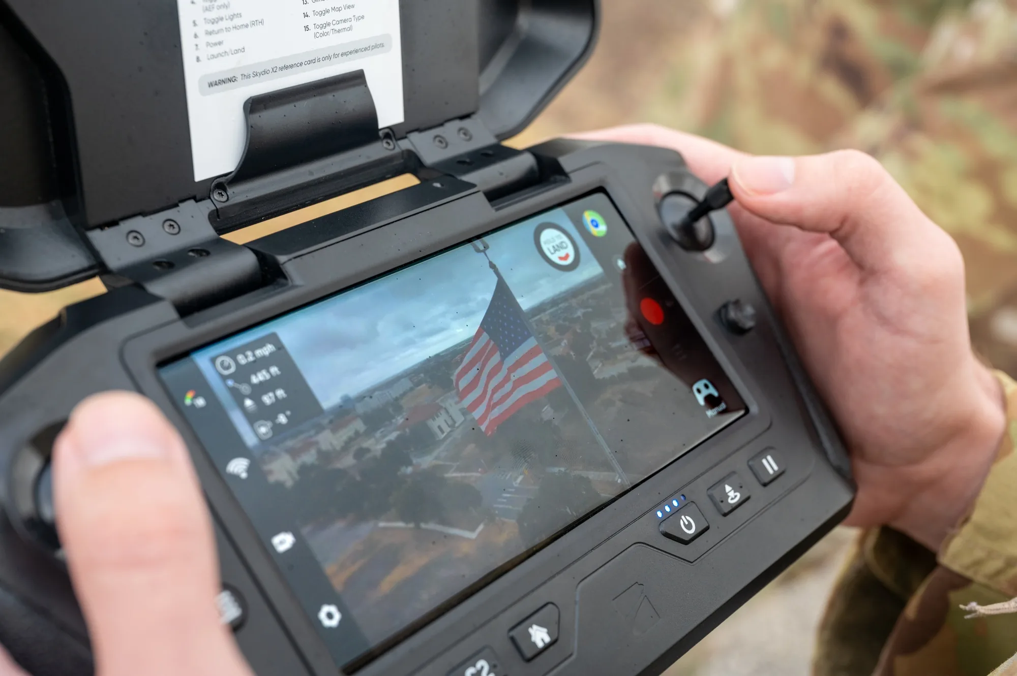 Hands operating a drone controller with an aerial camera view on its screen