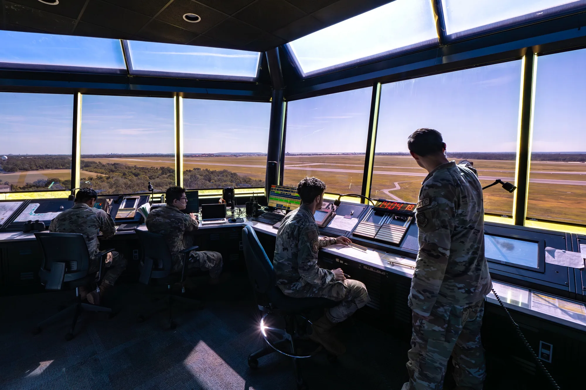 Four air traffic controllers work at consoles overlooking the runways at MacDill Air Force Base.