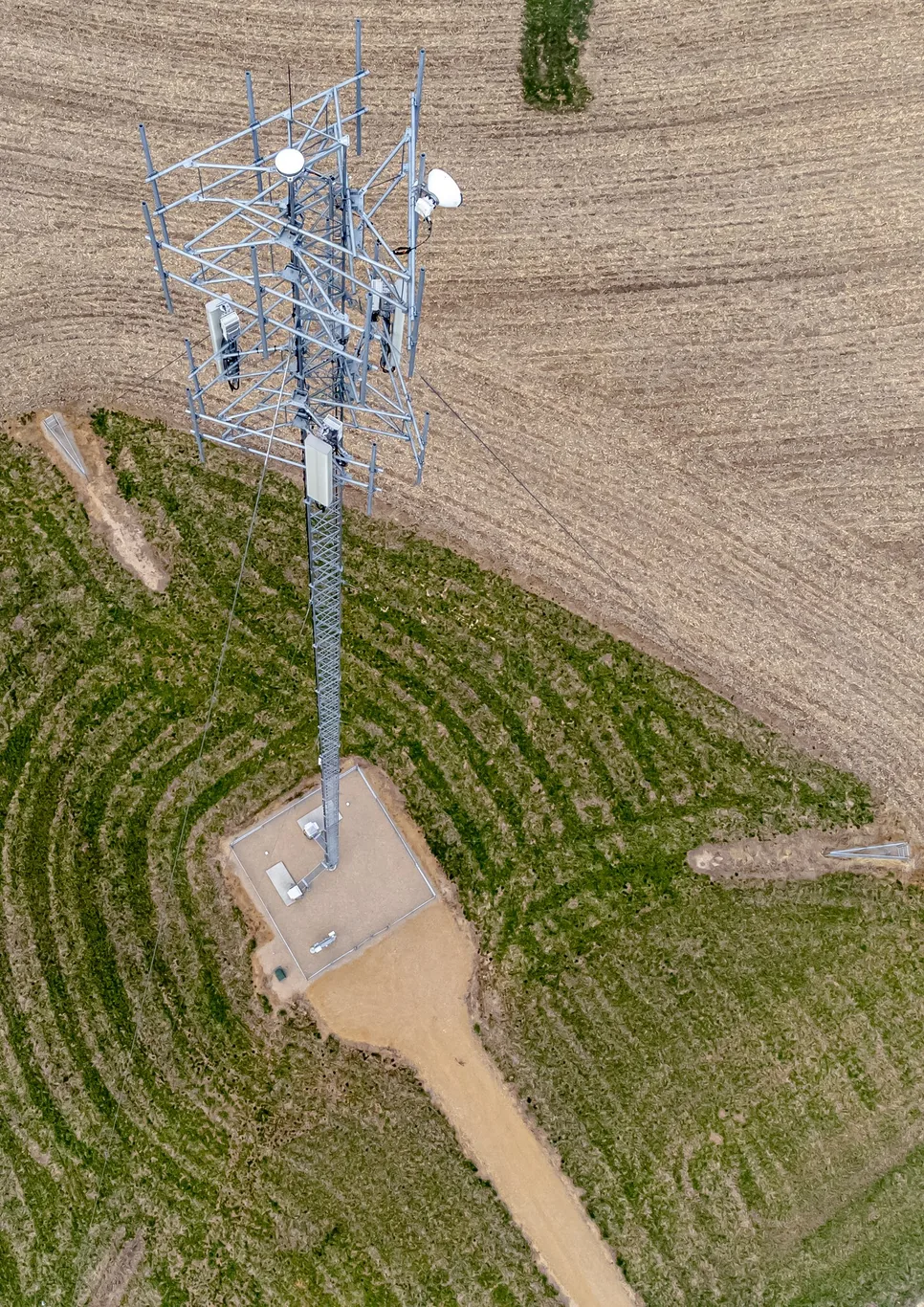 Aerial view of a lattice communications tower with antennas, guy wires and surrounding farmland