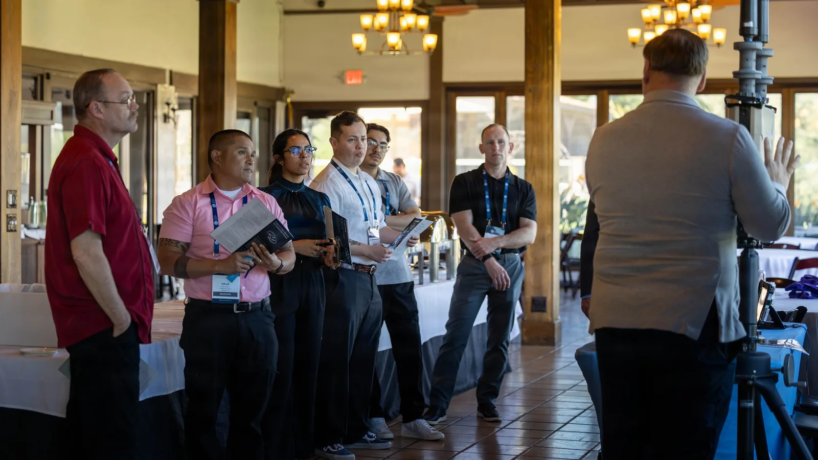 Industry partners wearing conference badges gather around a counter-UAS technology display at a professional event.
